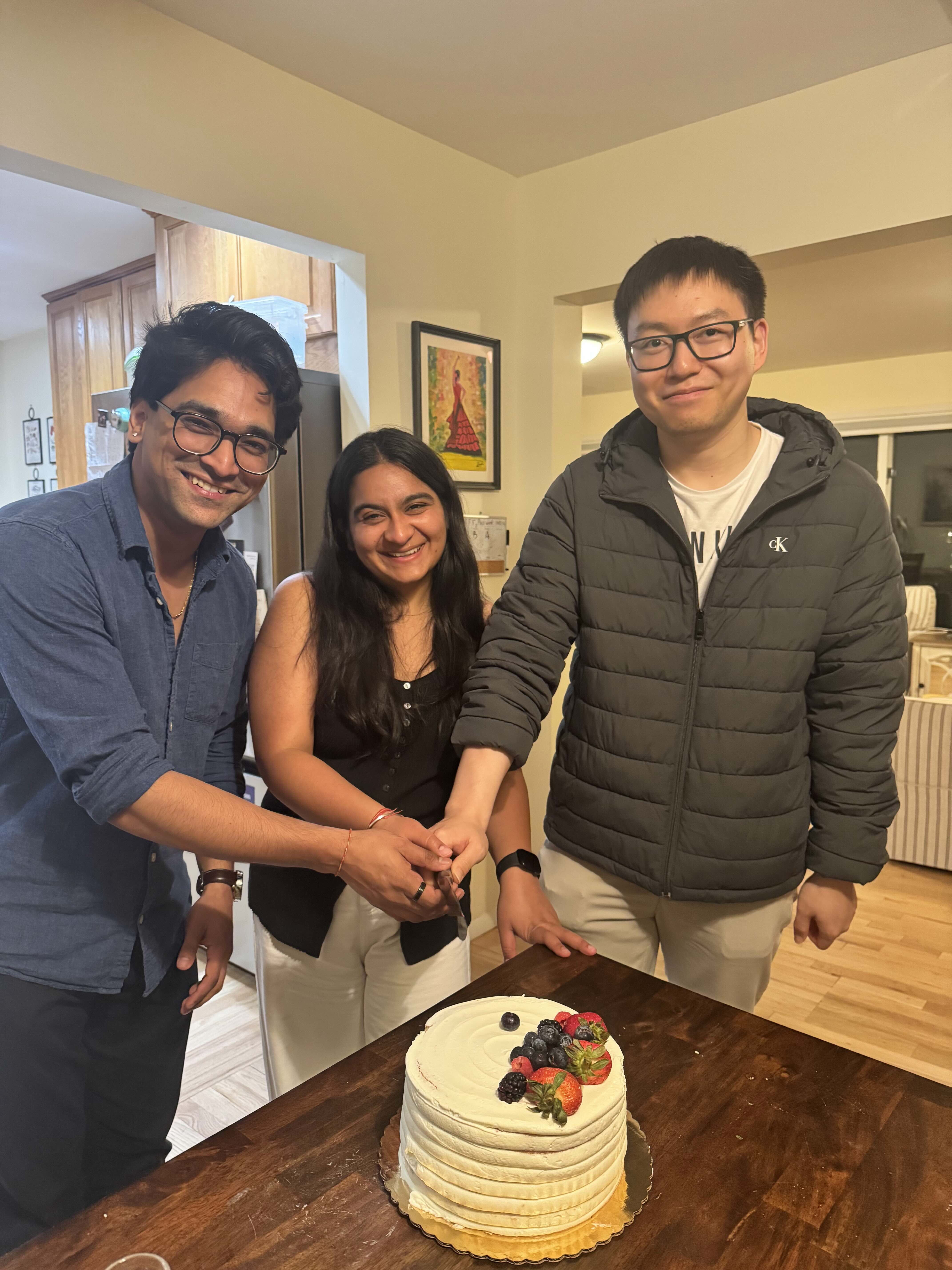 Tanmay, Prerna, and Zhengyu cutting cake for their farewell party